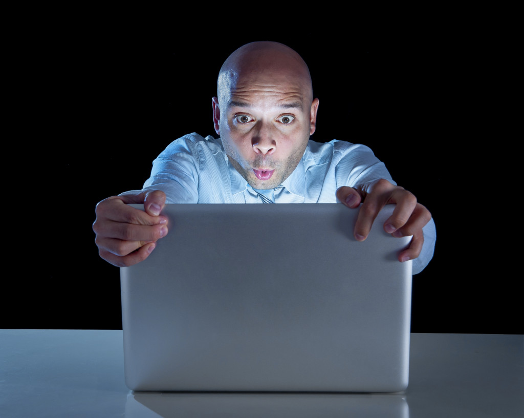 bald guy watching something on a laptop